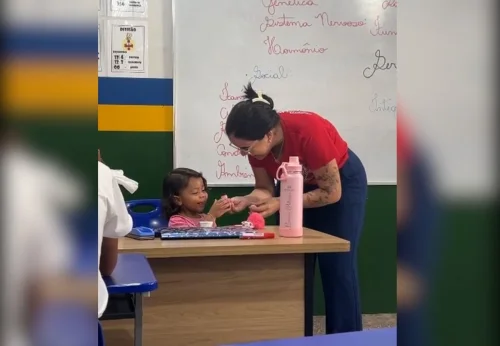 Professora segura filha de aluna no colo durante aula para que mãe possa estudar